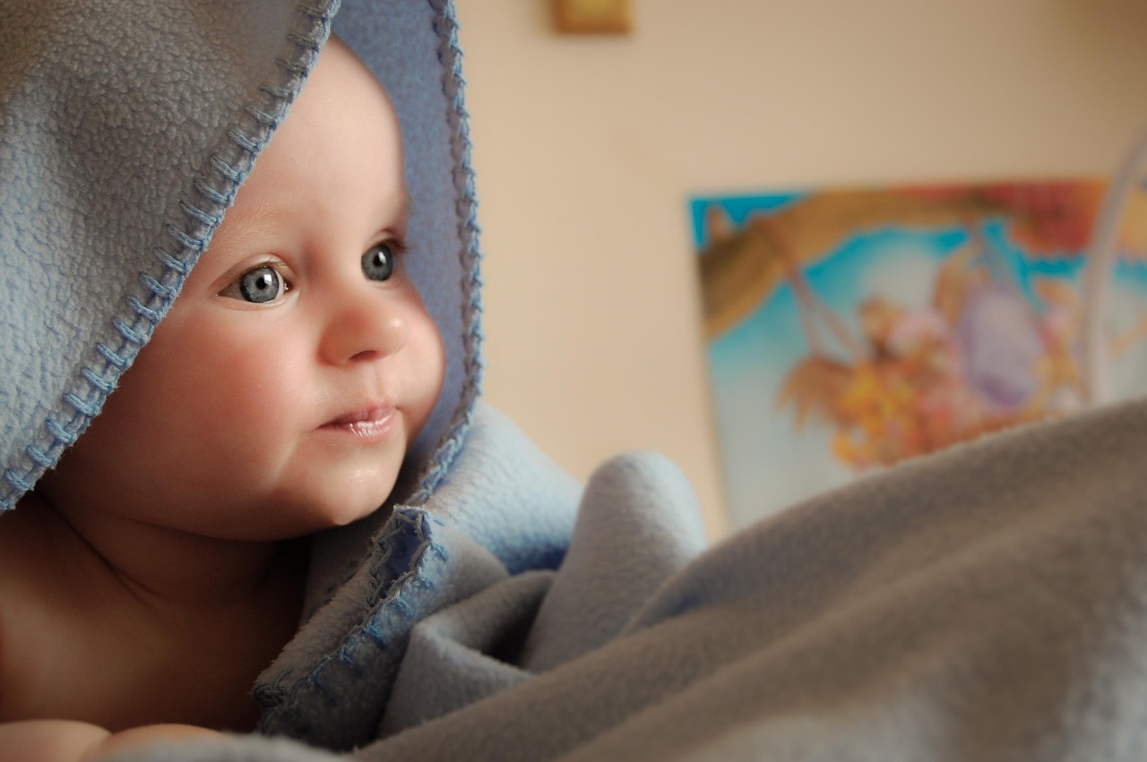 Un bébé avec une couverture l'enroulant telle une cape