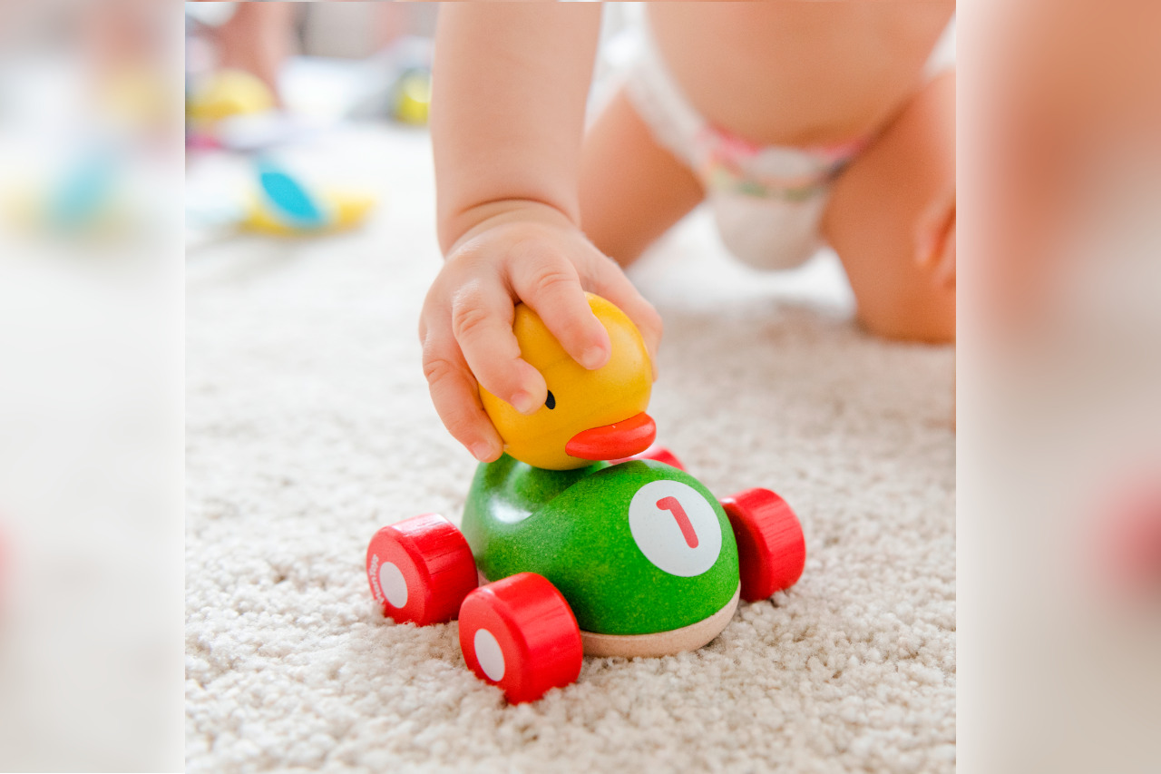 Bébé qui joue avec une petite voiture en bois